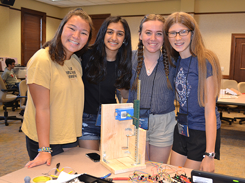 The four teammates proudly exhibit the 3D printer they designed and built.